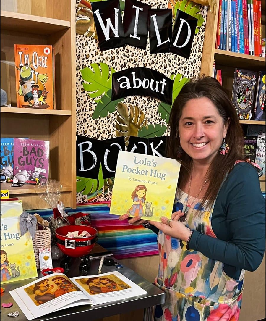 Courtney Owen holding Lola's Pocket Hug at a book display